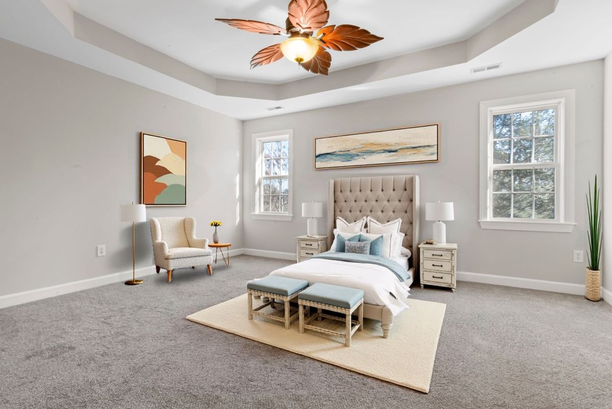 Virtually staged: the same primary bedroom with digitally added coastal furniture and decor, including wall art, lamps and plants; walls, windows, fixtures and floor unchanged